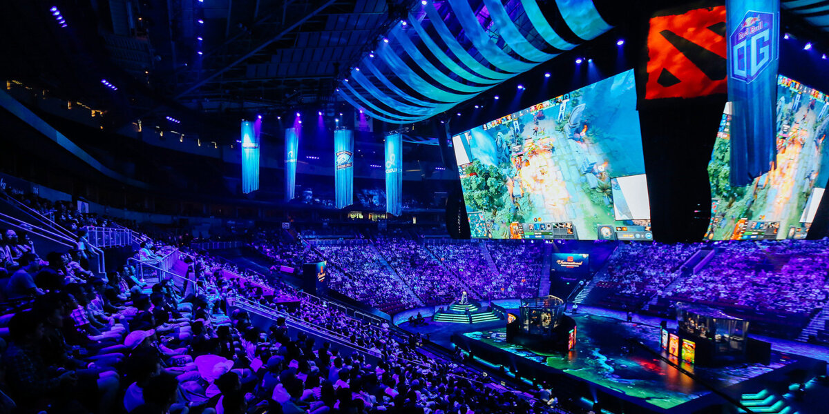 Volgepakt esportstadion met blauwe belichting en grote schermen toont een spannende live wedstrijd, bezocht door vele fans